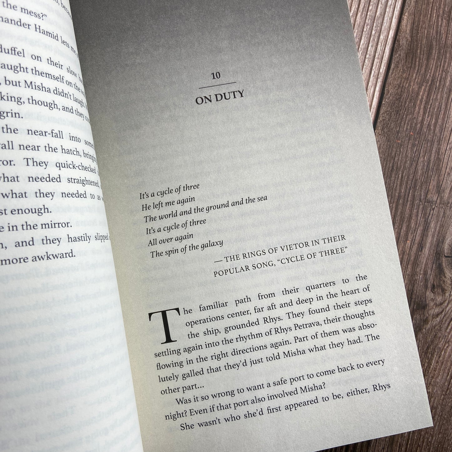 A paperback (titled "A Bid to Rule: The Stars and Green Magics - Book 3" by Novae Caelum) opened to display the first page of "Chapter 10: On Duty".
