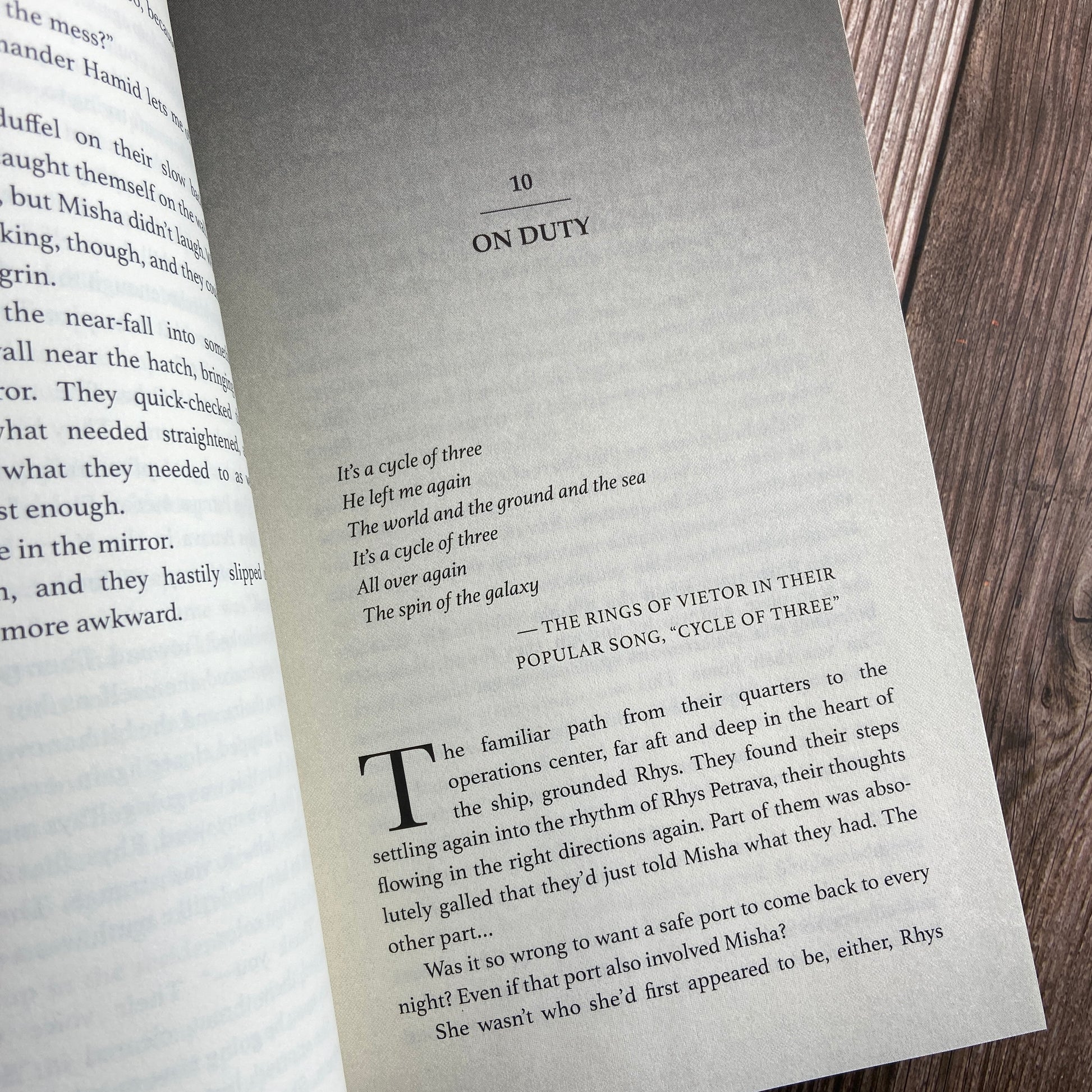 A paperback (titled "A Bid to Rule: The Stars and Green Magics - Book 3" by Novae Caelum) opened to display the first page of "Chapter 10: On Duty".