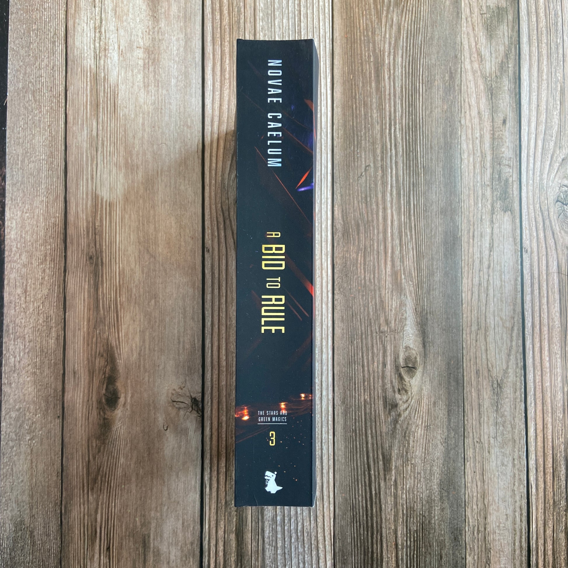Spine of paperback titled "A Bid to Rule: The Stars and Green Magics - Book 3" by Novae Caelum.