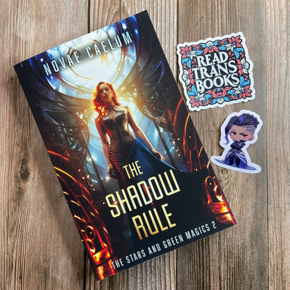 A SIGNED The Shadow Rule: The Stars and Green Magics Book 2 by Novae Caelum about shapeshifting abilities on a wood surface.