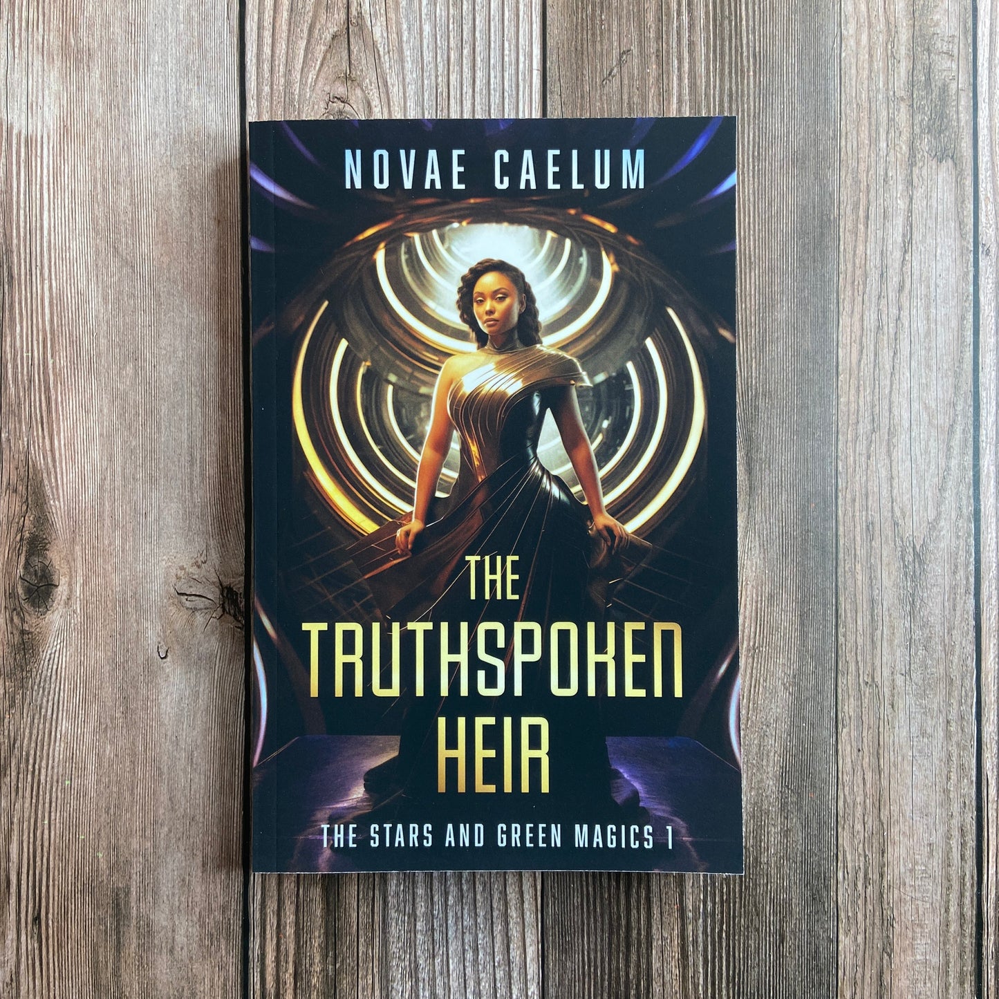 A paperback titled "The Truthspoken Heir: The Stars and Green Magics - Book 1" by Novae Caelum, featuring a cover image of a woman in a strapless, flowing gown standing with glowing rings in the background.
