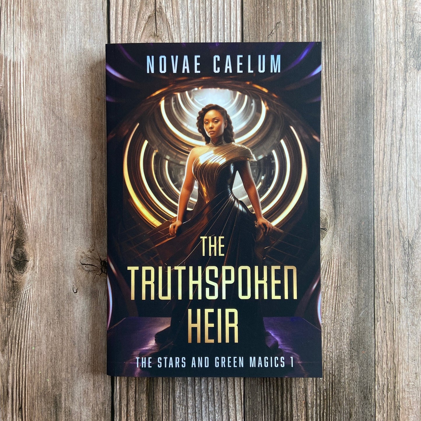 A paperback titled "The Truthspoken Heir: The Stars and Green Magics - Book 1" by Novae Caelum, featuring a cover image of a woman in a strapless, flowing gown standing with glowing rings in the background.