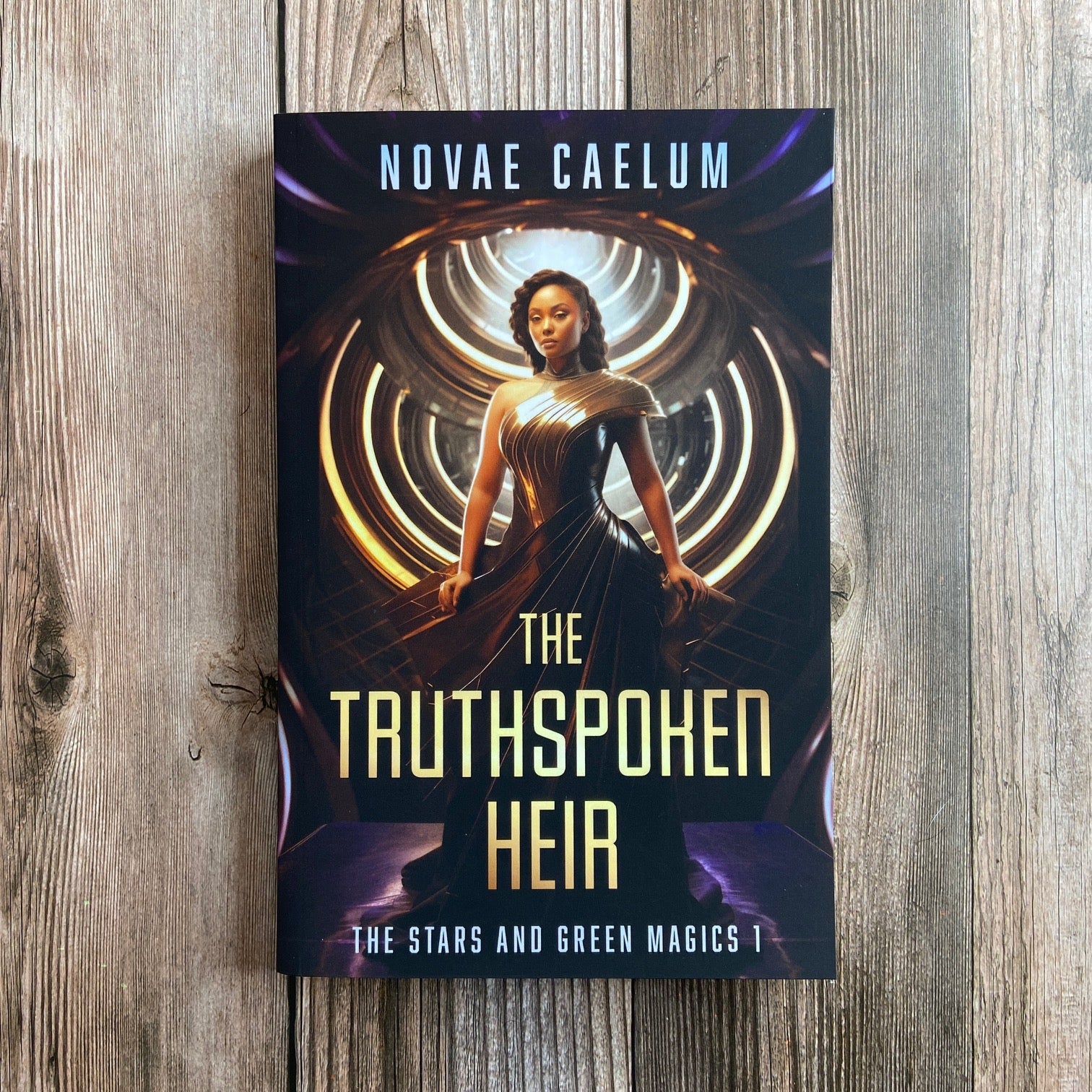 A paperback titled "The Truthspoken Heir: The Stars and Green Magics - Book 1" by Novae Caelum, featuring a cover image of a woman in a strapless, flowing gown standing with glowing rings in the background.