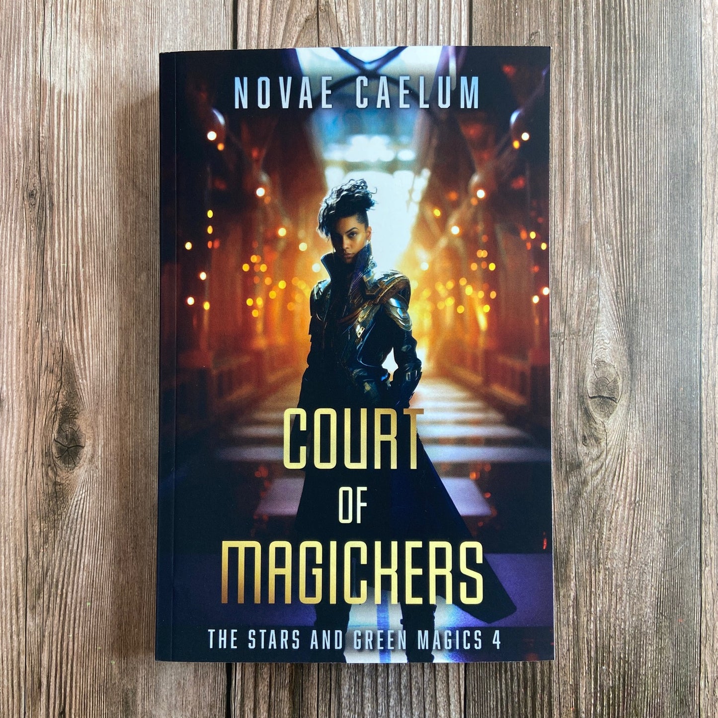 A paperback titled "Court of Magickers: The Stars and Green Magics - Book 4" by Novae Caelum, featuring a cover image of a nonbinary individual in a futuristic gown standing with glowing hallway in the background.