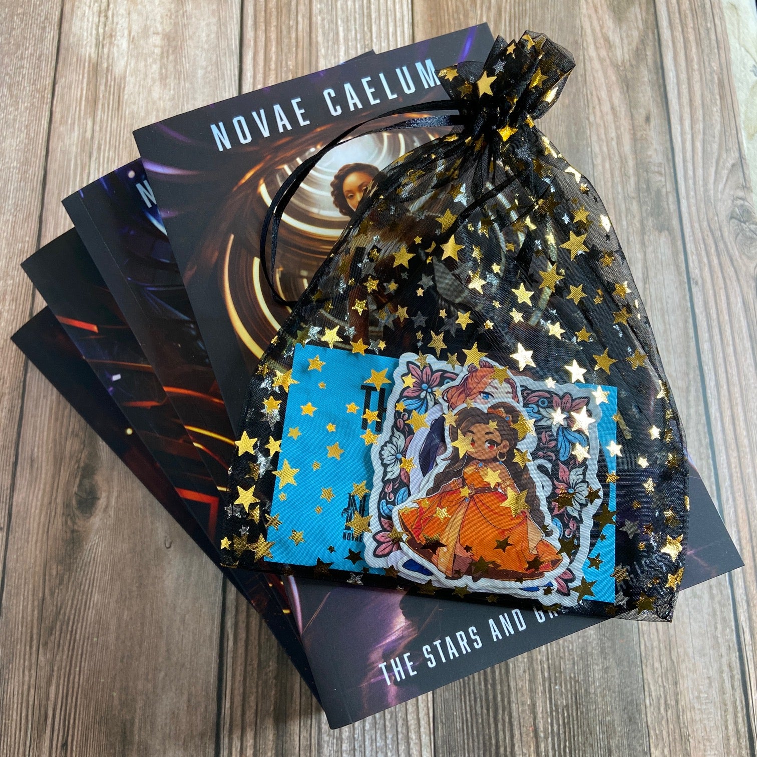 Stack of 4 paperbacks (Books 1-4) from "The Stars and Green Magics" series by Novae Caelum displaying the spines, along with a black, starry mesh gift bag filled with a variety of series-related stickers.