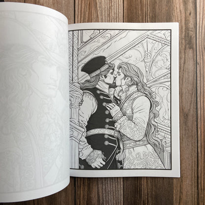 A coloring book (titled "The Gay Pirate Coloring Book: Coloring Stress Relief for Adults" by N.C. Starshadow) opened to display a black-line image of two gay pirates kissing.