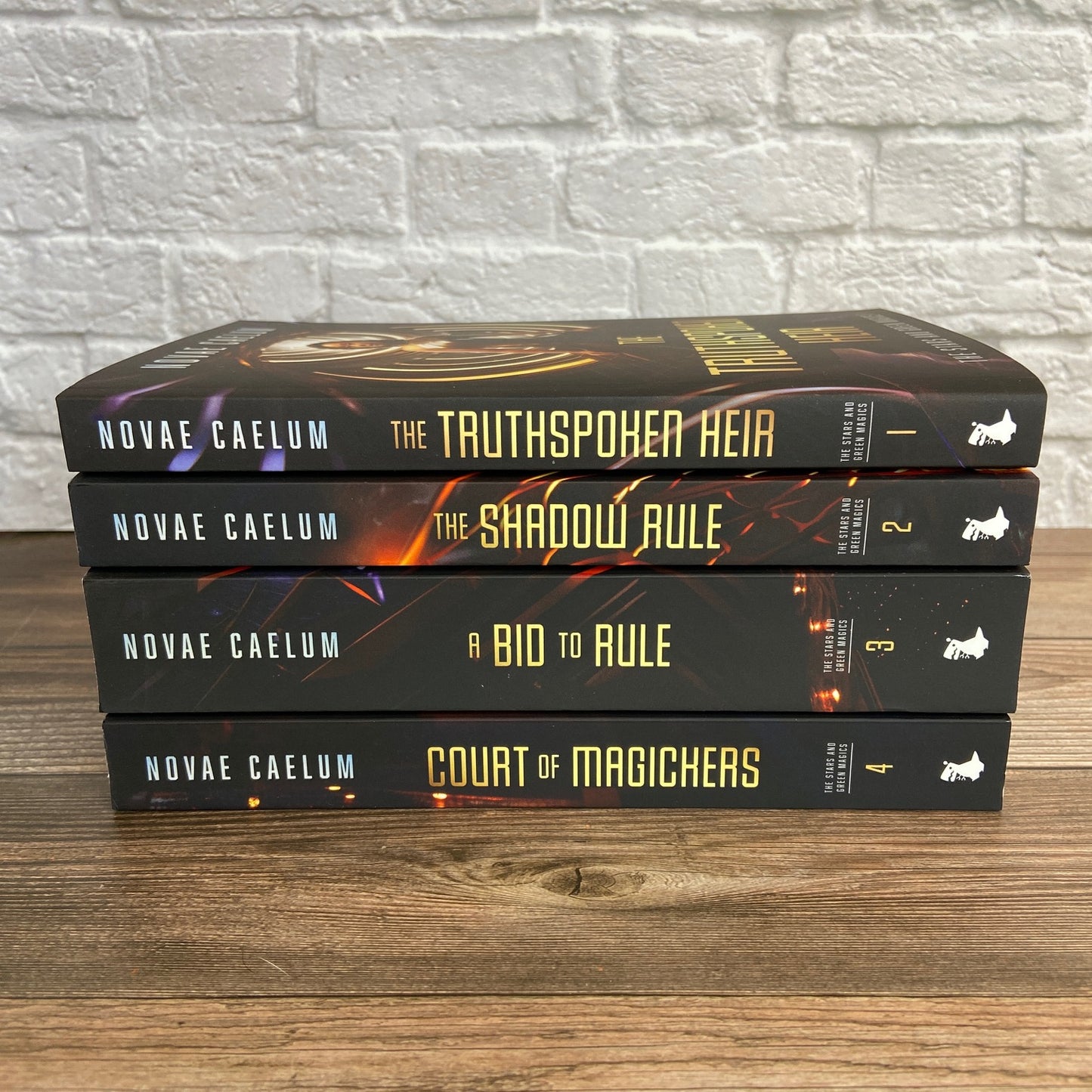 Three Novae Caelum SIGNED Paperback Bundles: The Stars and Green Magics (Books 1-4) on a wooden table, one featuring trans and nonbinary main characters.