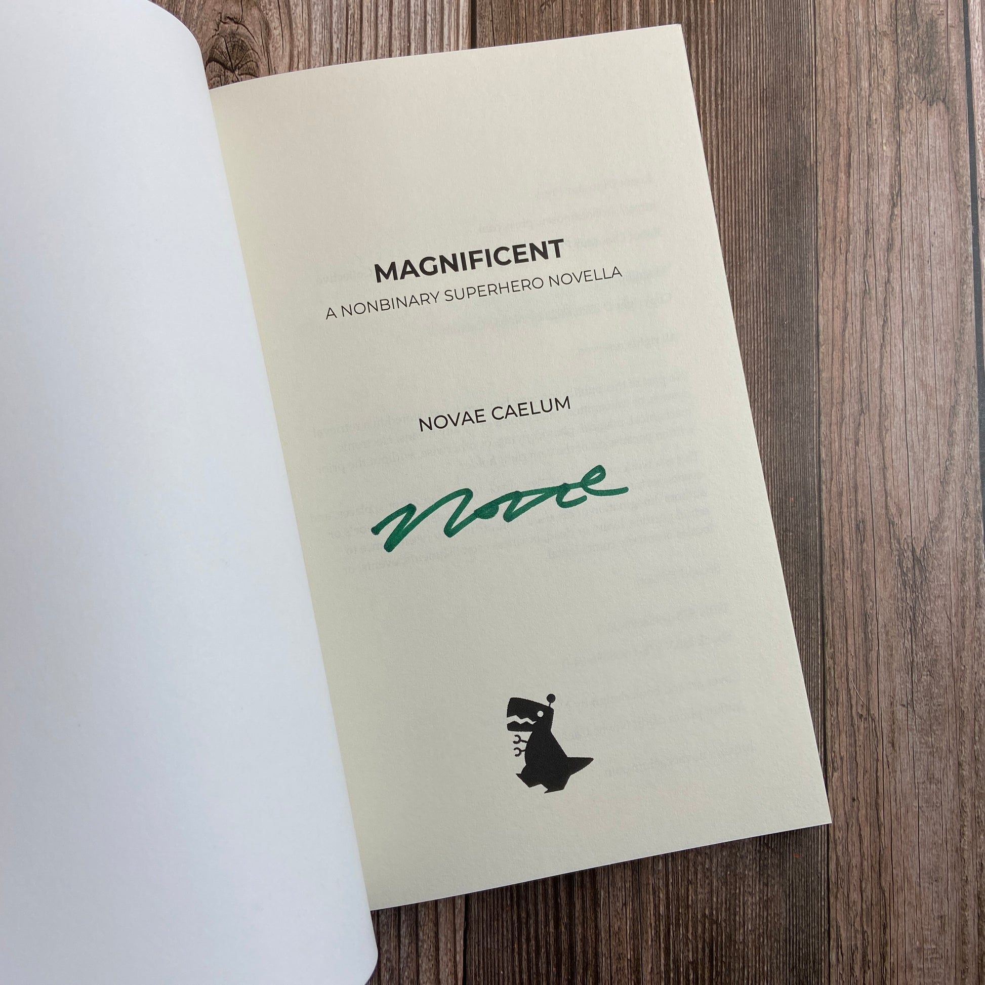 A SIGNED Magnificent: A Nonbinary Superhero Novella (Paperback) by Novae Caelum rests on a wooden table.