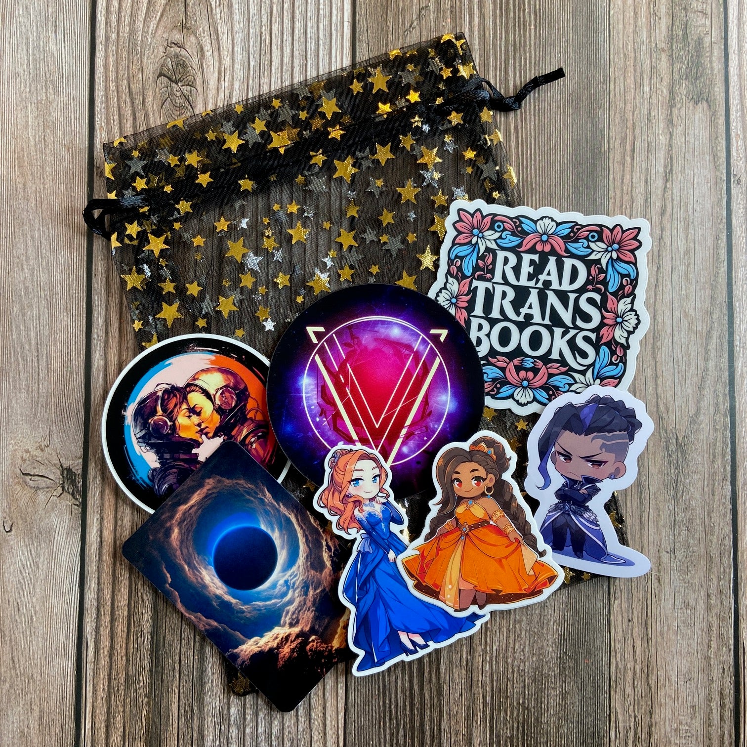 A black, starry mesh gift bag filled with a variety of series-related pieces of swag from Books 1-4 of "The Stars and Green Magics" series by Novae Caelum.